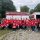 Group of people in red shirts posing in front of a Rabun County Fire engine.