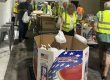 Volunteers in high-visibility vests sorting donation boxes in a warehouse.