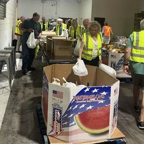 Volunteers in high-visibility vests sorting donation boxes in a warehouse.