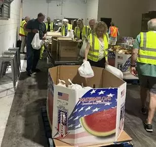 Volunteers in high-visibility vests sorting donation boxes in a warehouse.